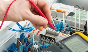 Elektryk sprawdza napięcie multimetrem. Zastanawiasz się, ile za punkt elektryczny?