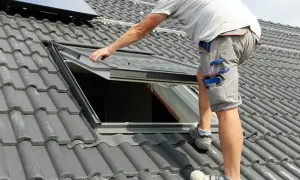 Instalacja okna dachowego na szarym dachu.