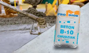 Wylewanie i wyrównywanie betonu na podbudowie, obok worek z betonem B-10 Chudziak.