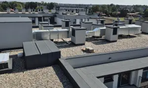 Widok na nowoczesny dach balastowy z licznymi elementami wentylacyjnymi i okapami.