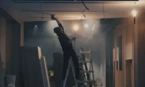 Remont wnętrza: pracownik na drabinie szlifuje sufit, w tle materiały budowlane i lampy.