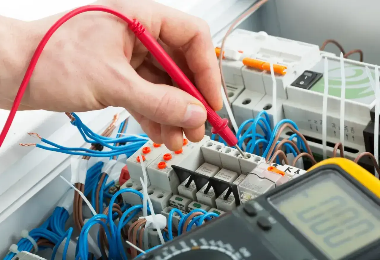 Elektryk sprawdza napięcie multimetrem. Zastanawiasz się, ile za punkt elektryczny?