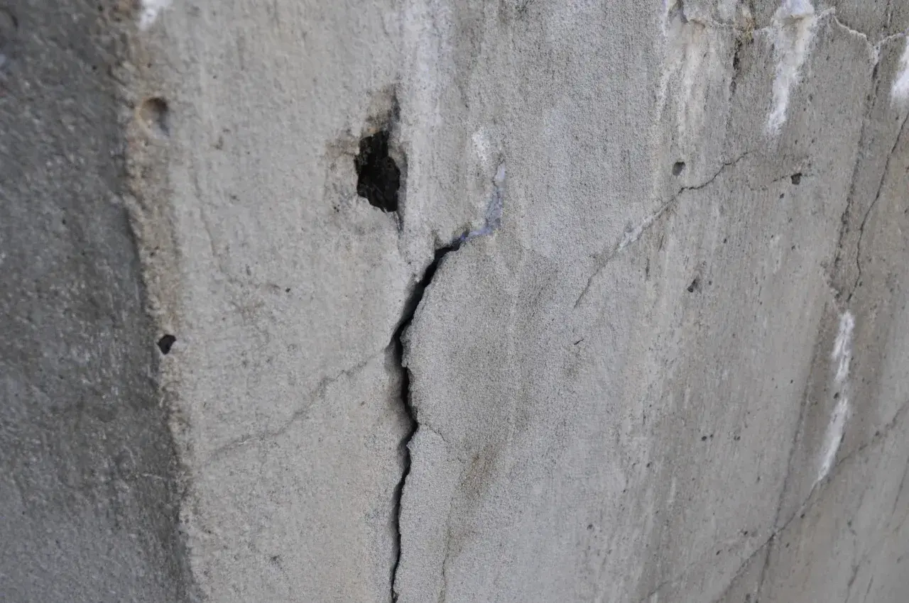 Pęknięty beton z widocznym otworem i drobnymi ubytkami.