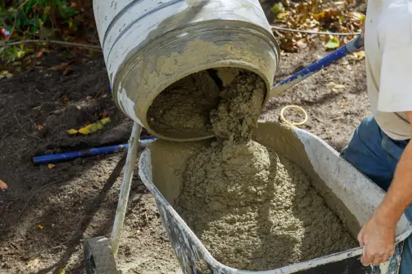 Betoniarka wylewa świeży beton do taczki.