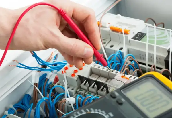 Elektryk sprawdza napięcie multimetrem. Zastanawiasz się, ile za punkt elektryczny?