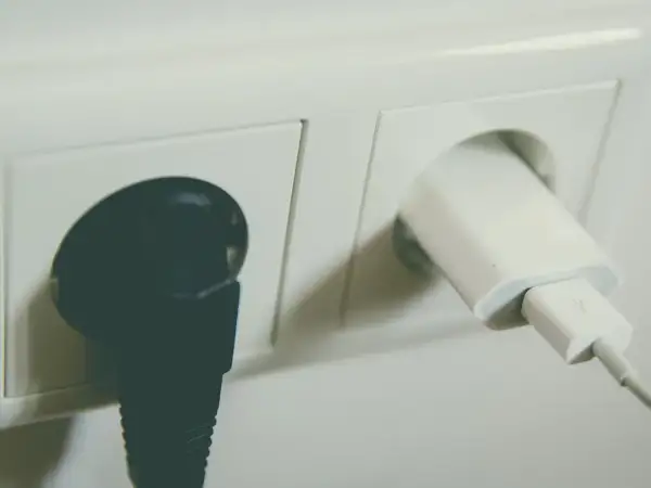 Dwa gniazdka elektryczne: jedno z czarną wtyczką, drugie z białą ładowarką USB. Sprawdź montaż gniazdka cena.