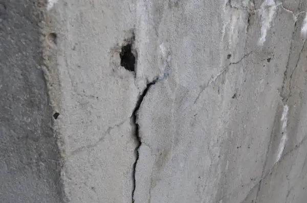Pęknięty beton z widocznym otworem i drobnymi ubytkami.