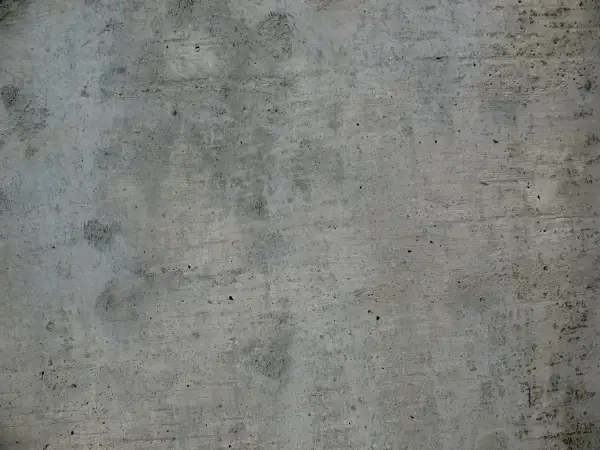 Szara, chropowata powierzchnia betonu z widocznymi nierównościami i śladami po szalunku.