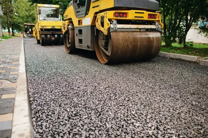 Walec drogowy ubija świeży asfalt, tworząc gładką nawierzchnię. Tak wygląda pospółka po pracy walca.